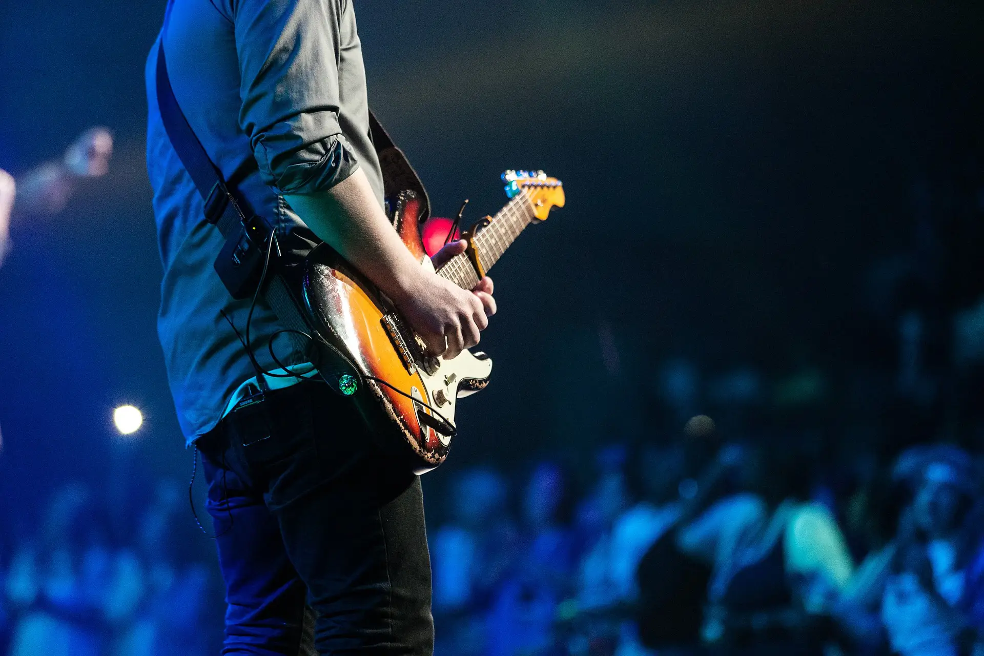 In the picture, a man playing the guitar in front of a crowd.